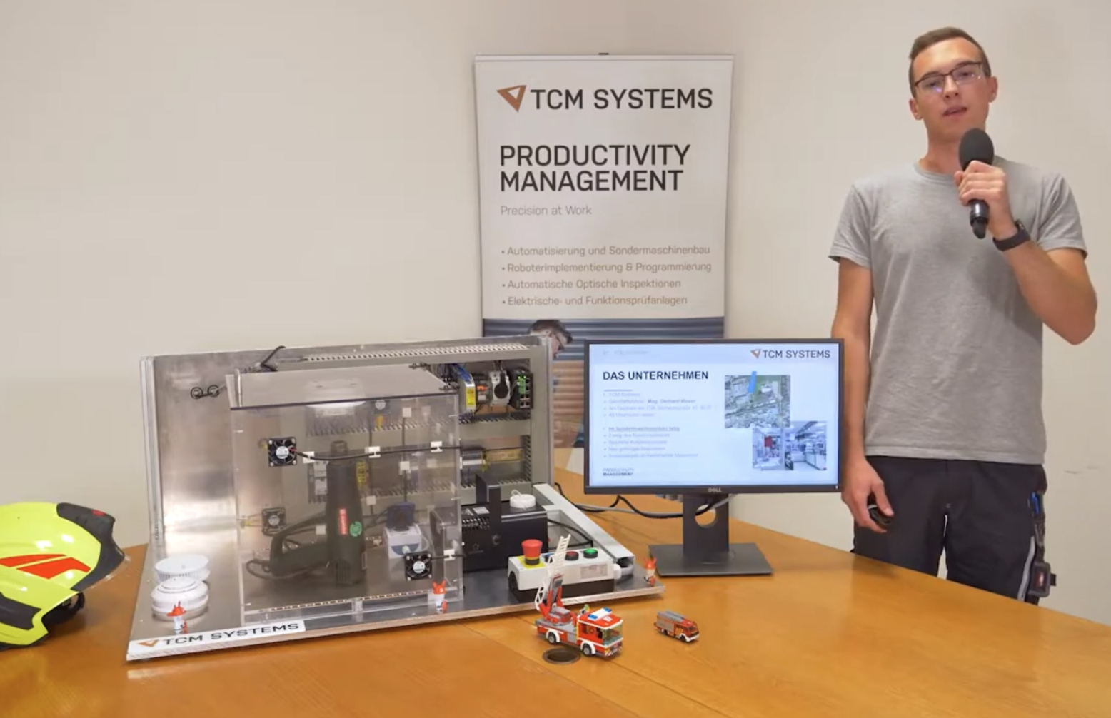 Präsentation des Lehrlingswettbewerbs. Projektvorstellung von TCM Systems, ein Projektmitarbeiter mit Mikrofon stellt das Projekt vor.