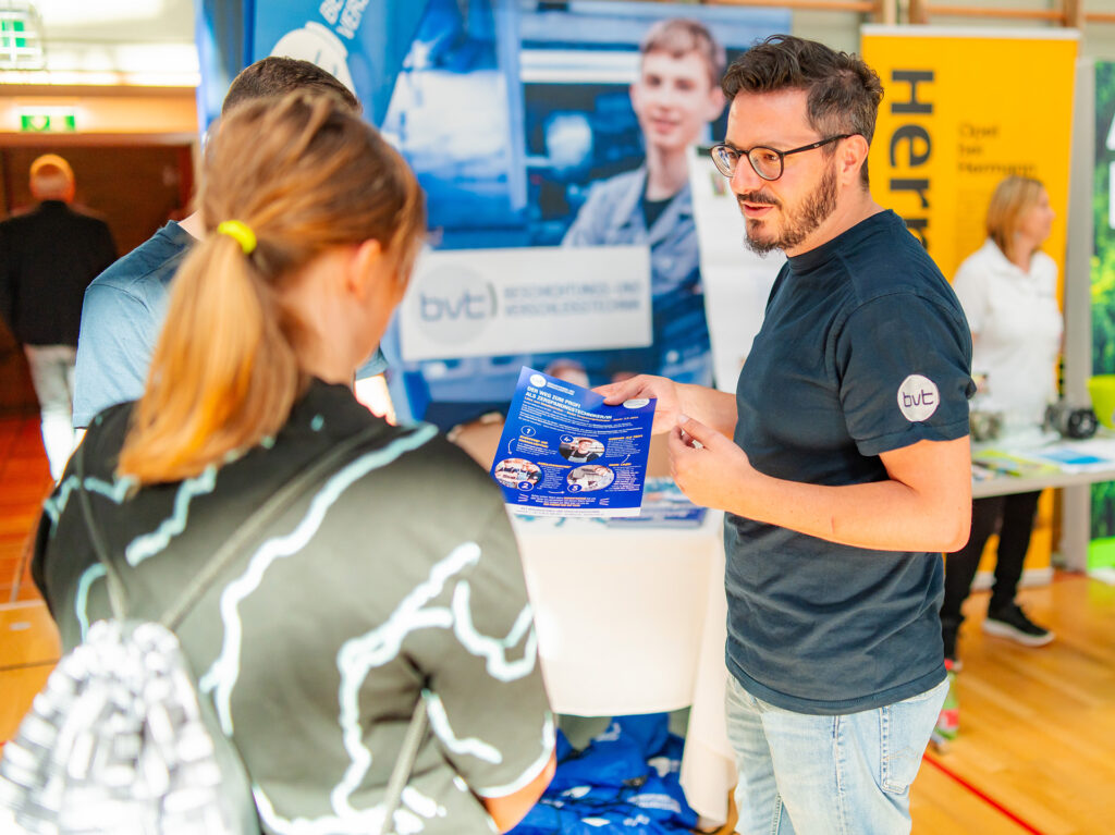 Zwei Messebesucher am Messestand des bvt mit Infobroschüre.