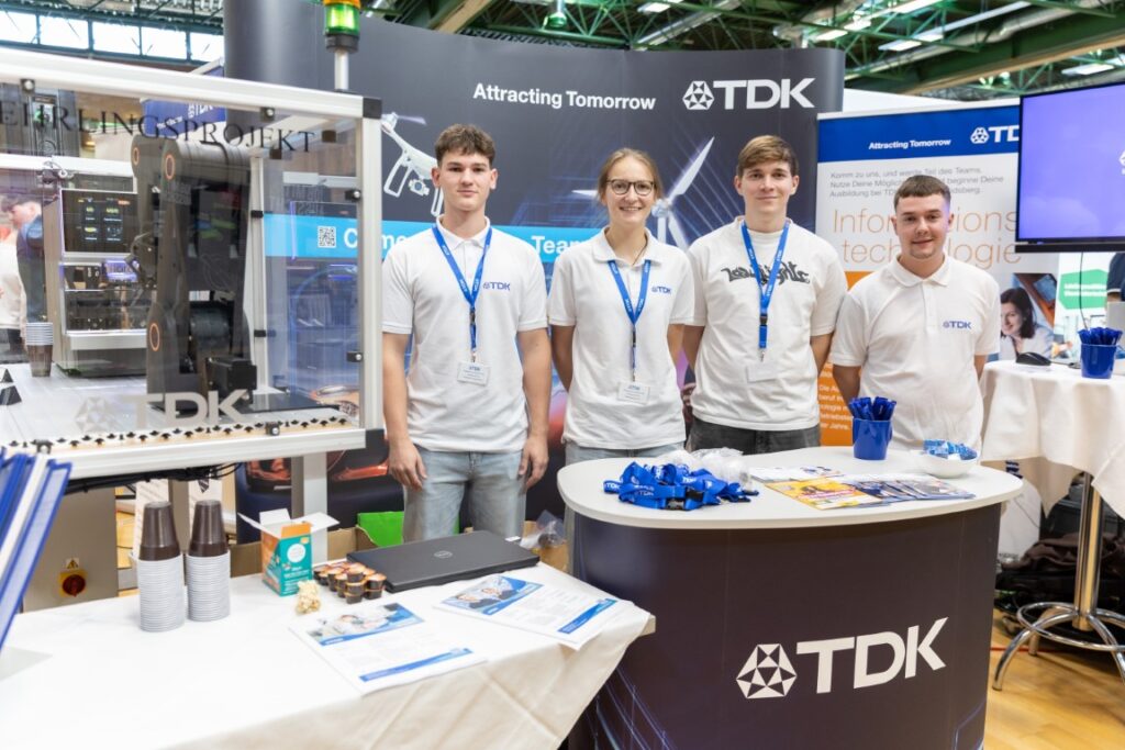 Vier Mitarbeiter von TDK am Messestand von TDK.