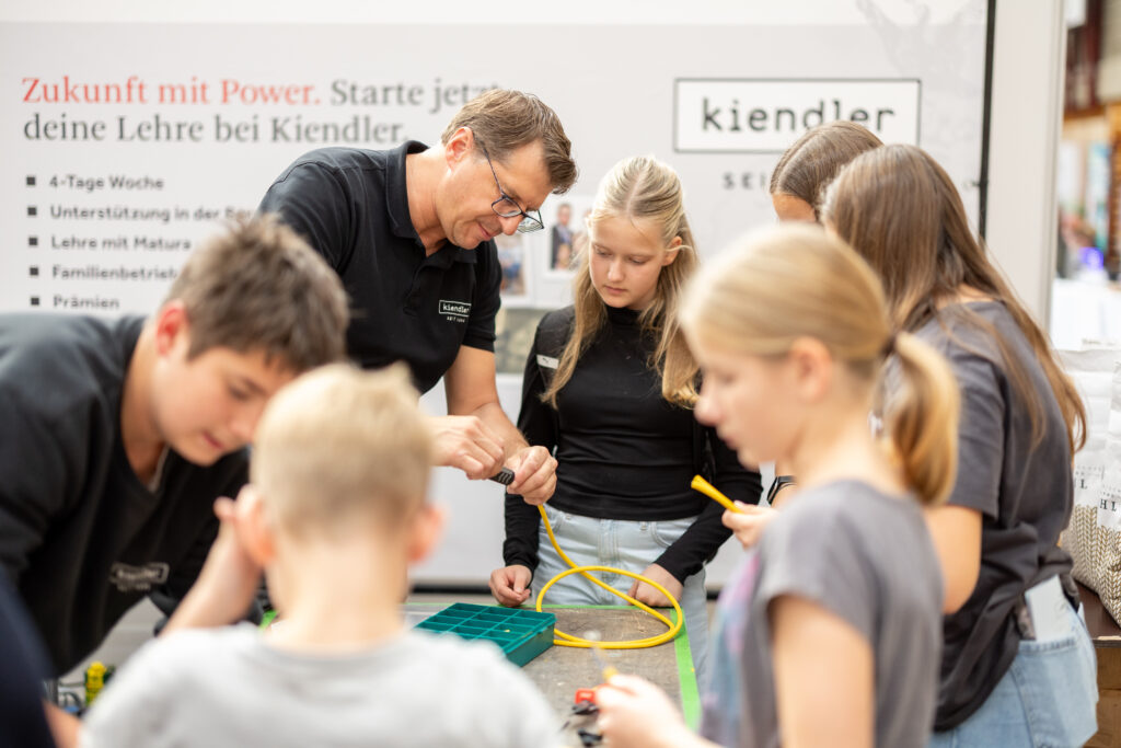 Ein Mitarbeiter der Firma Kiendler gibt in der Veranstaltungshalle Kindern einen Einblick in seine Arbeit.